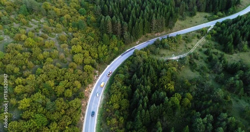 Aerial view of cars driving on a winding mountain forest road
