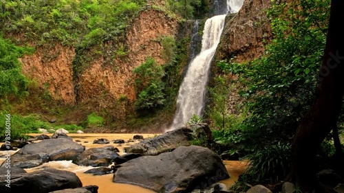waterfall, lush green foliage, mossy rocks, serene landscape, natural environment, flowing water, sunlight, tranquil atmosphere, peaceful scenery, adventurous exploration
