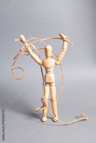 Wooden puppet with strings on gray background. Concept of emotional manipulation,dictatorship and control