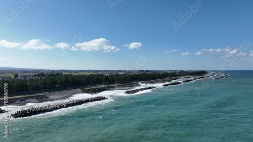 冬が近く風の強い富山湾沿岸の洋上風力発電風車や波のかかる離岸堤などの風景