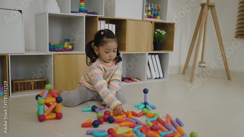 happy toddler girl playing colorful magnetic construction toy