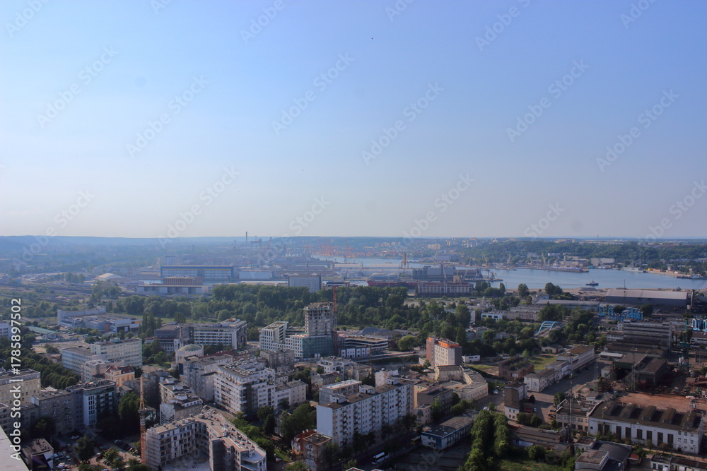 Fototapeta premium Panoramic view of industrial city with port and cranes on summer day