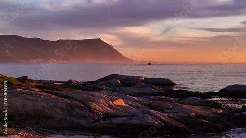Aerial view of the rocky coastline near Cape Town, where the sun kisses the horizon, painting the sky in hues of orange and pink, Cape Town, Western Cape, South Africa.