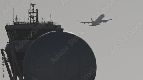 airplane flying past air traffic control tower 