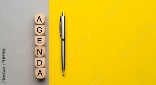 Bright yellow agenda with pen and wooden blocks spells 'agenda' for effective planning and modern business meetings - stay organized today!