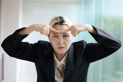 Papier peint A stressed, frowning middle-aged Caucasian businesswoman knitting her brow with