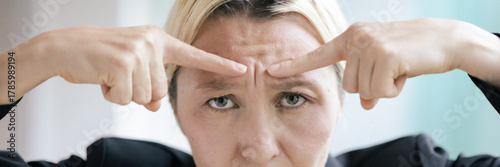 A stressed, frowning middle-aged Caucasian businesswoman knitting her brow with a stressful and worried expression, feeling overwhelmed and under pressure at work, real woman, female person model