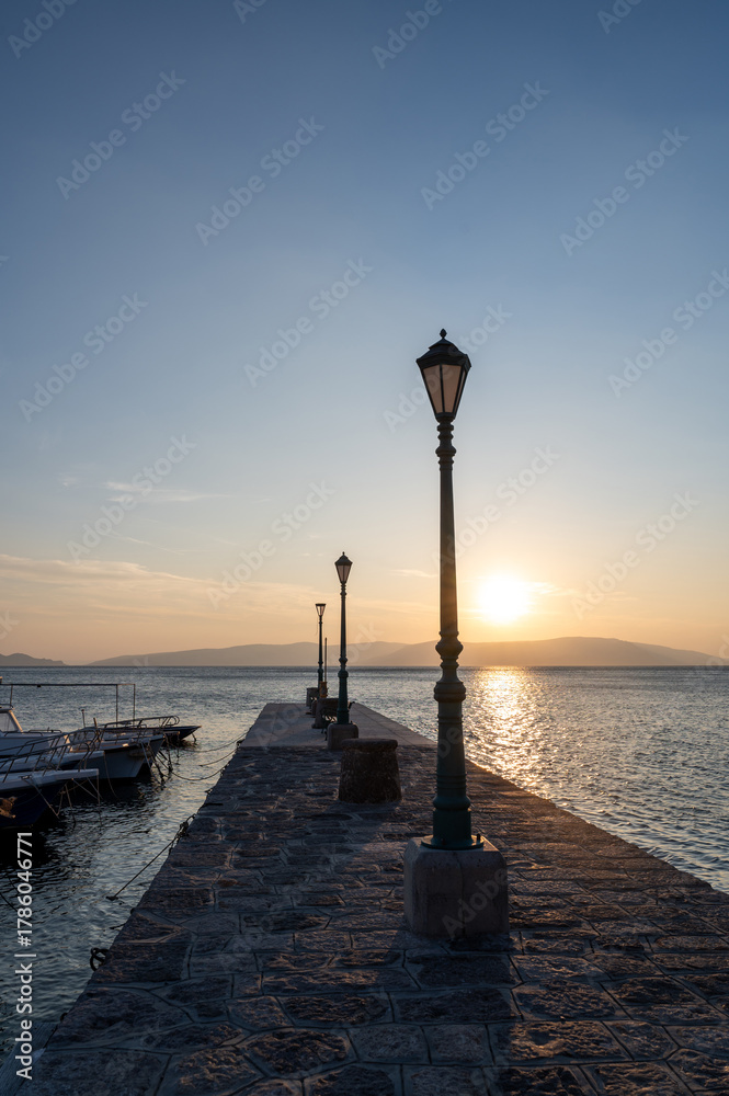 Fototapeta premium Lanterns on a pier with boats, by the sea at sunset