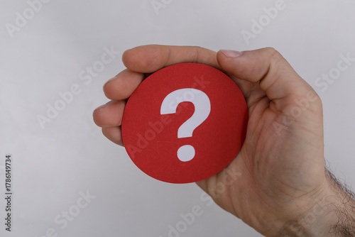 A hand holds a red question...