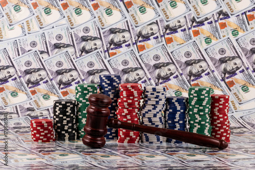 A judge's gavel and casino betting chips against a backdrop of $100 bills
