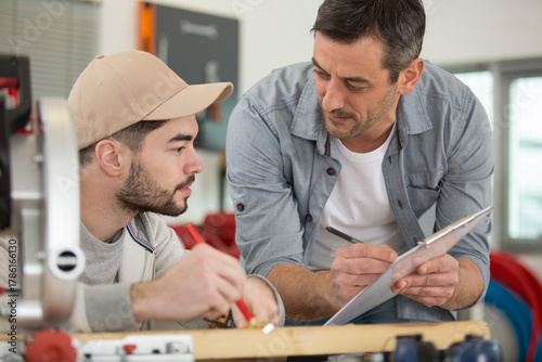 supervisor with clipboard talking to his apprentice