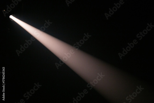 Apenas um feixe de luz de palco, em ambiente totalmente escuro.