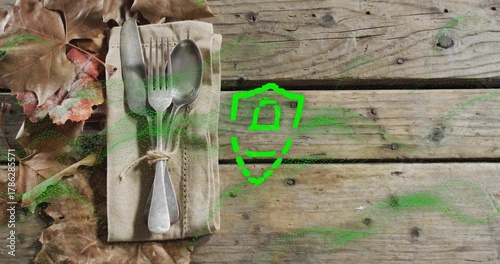 Placing beige napkin with three utensils and twine on wooden tabletop, green shield, copy space