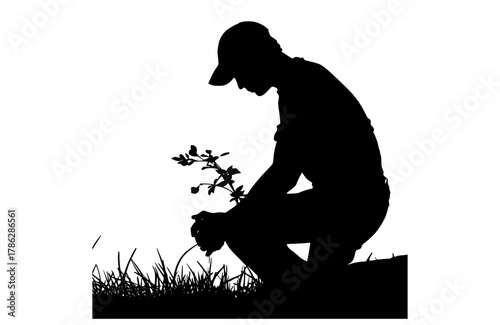 a silhouette of a man kneeling down to plant a treebaseball hat, floor, flower, gardener, grass, land, man, person, plant, profile, squat, stump, tree, weed 