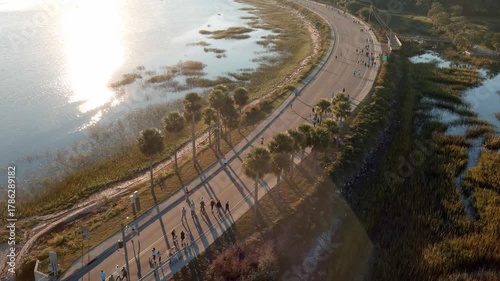 Tracking aerial drone shot of a running race during early morning with lens flare.