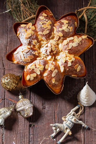A star or snowflake shaped cupcake decorated with almond flakes, a wreath and Christmas tree decorations.