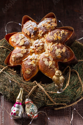 A star or snowflake shaped cupcake decorated with almond flakes, a wreath and Christmas tree decorations.