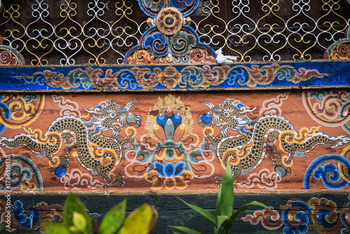 View of intricate dragon murals dance across the weathered facade of Kyichu Lhakhang, under ornate latticework, in Paro, Bhutan.