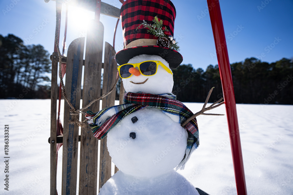 Obraz premium Snow man with festive decorations. Snowman in wintry backyard. Funny snowman with joyful expression outdoors. Snowman with scarf and hat for winter banner. Snowman in winter scene.