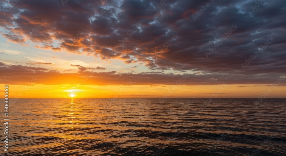 Obraz premium Dramatic golden hour colors paint the vast sky above the calm ocean horizon as the sun dips below the water line creating a stunning view ,twilight ,red ,tropical