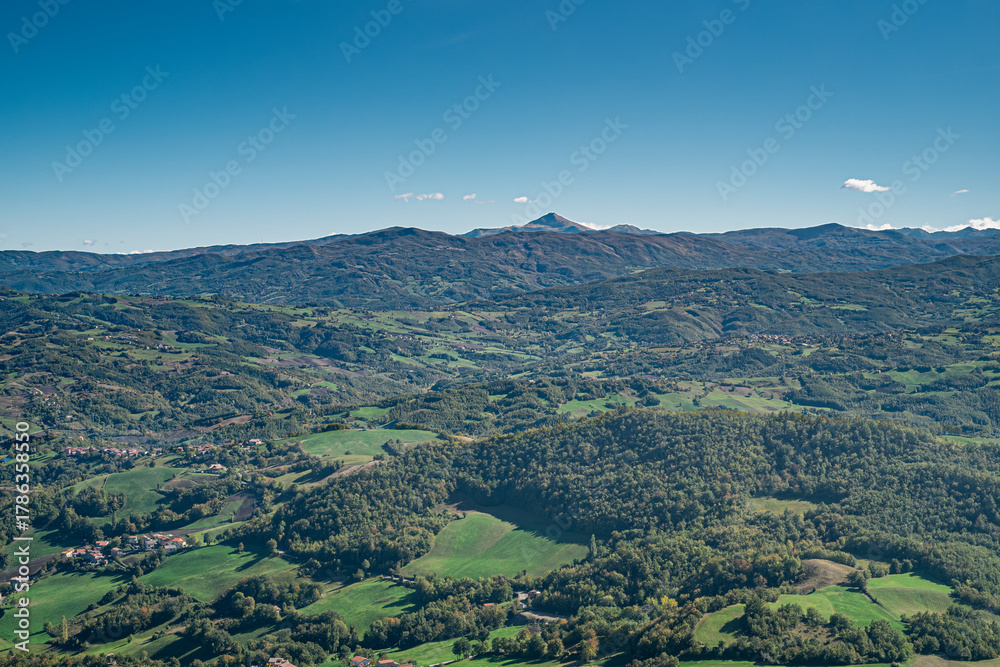 Obraz premium The mountains, forests, pastures and villages where Parmigiano-Reggiano is produced. Provinces of Modena and Reggio Emilia, Italy. Taken from the Pietra di Bismantova; Mount Cimone on background