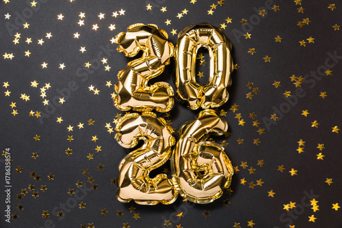 New year 2026 balloon celebration card. Gold foil helium balloons number 2026, party decoration, golden confetti stars on dark background. Flat lay, merry christmas banner, happy holidays concept.