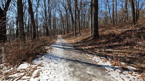 hiking on snowy and icy trail in park on sunny January day