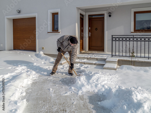 Man clearing path to his house of snow with shovel after heavy snowing