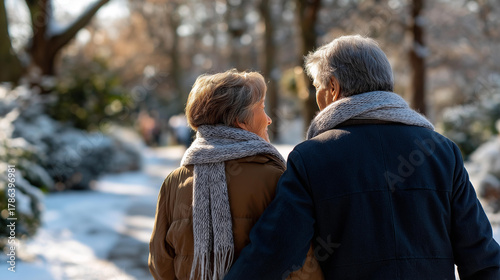 Fototapeta Naklejka Na Ścianę i Meble -  Faceless elegant senior couple walking in snowy park defocused winter landscape background during cold snowy day mature romance leisurely winter stroll with copy space