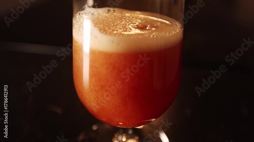 Dark craft lager beer being poured in beer glass, dark environment and light effect.