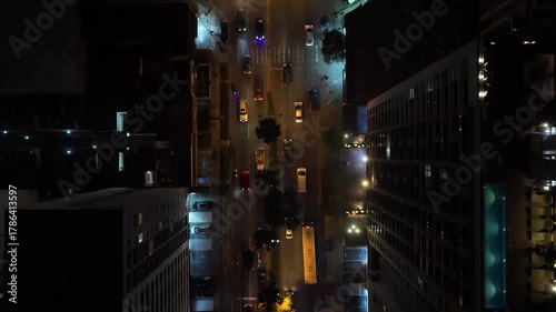 Top down aerial view of traffic flowing through an illuminated city street in Lima, Peru, surrounded by modern buildings and skyscrapers