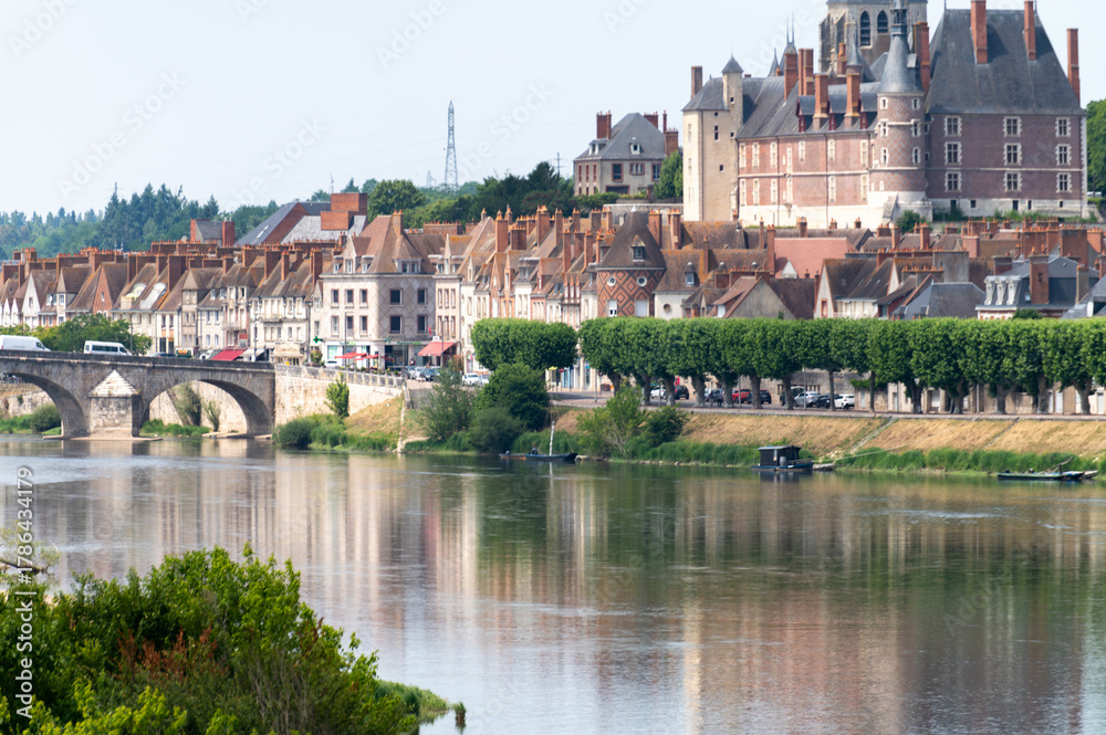Fototapeta premium Views of old part of town of Gien on the Loire river, in Loiret department, France, houses with tiled roofs and chimneys, castle and bridge