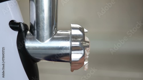 An electric meat grinder grinds meat into minced meat. Side view. Macro photography.