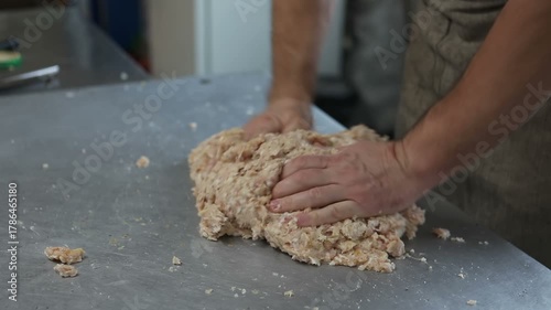 The cook mixes the minced meat, beating it on the table. A man prepares the minced meat for cutlets.