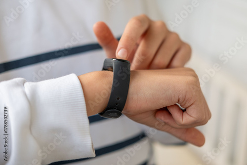 young teenager checking smart watch on wrist, child interacts with smartwatch, fitness band, trend wearable technology monitoring kids' daily activity and promoting healthy habits, activity tracker