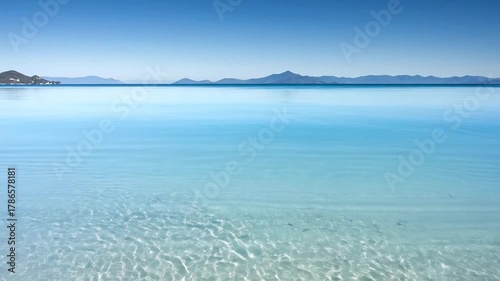 Tranquil Beach Scene: Calm Water, Mountains, and Sky