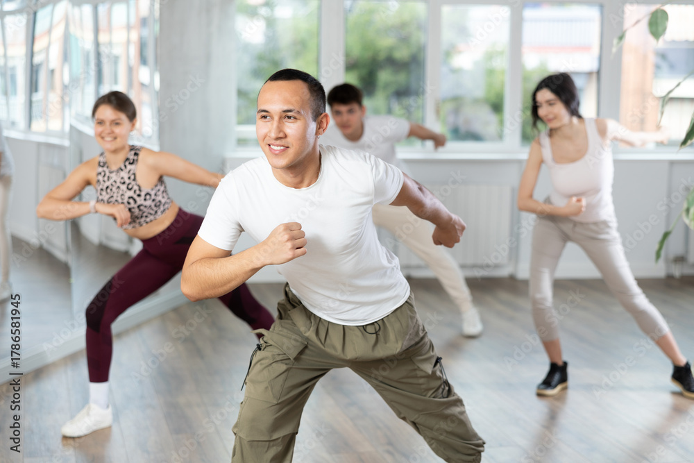 Naklejka premium Smiling people practicing vigorous lindy hop movements in dance class