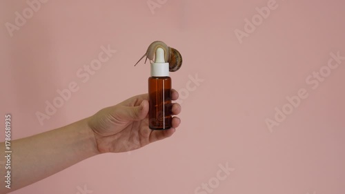 Video. Cosmetic bottle with snail on it in hand. Spa, naturale, luxury, cosmetics product, jar of anti-aging cream