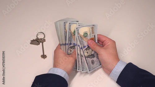 Close up video of business in suit counting money at the table with key on it. Business, finance, economy, deal, earnings, expenses. 