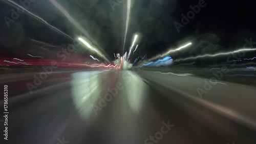 Dynamic night city time-lapse filmed from a moving car, showing bright light trails from traffic and streetlights. Perfect for urban, travel, or nightlife themed video projects.