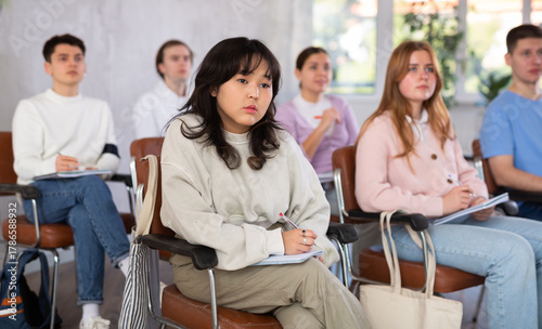 Картината върху платно High school students sit at their desks and listen carefully to the teacher at t