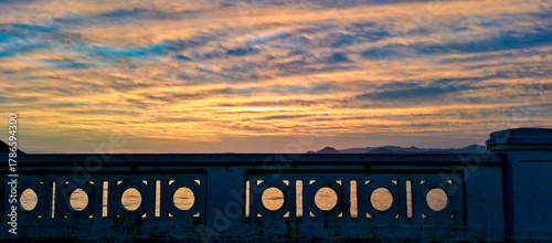 Beautiful sunset view over the ocean in Santos, São Paulo, Brazil, seen through the traditional seaside balustrade. The colorful sky and calm sea create a peaceful and scenic coastal atmosphere.
