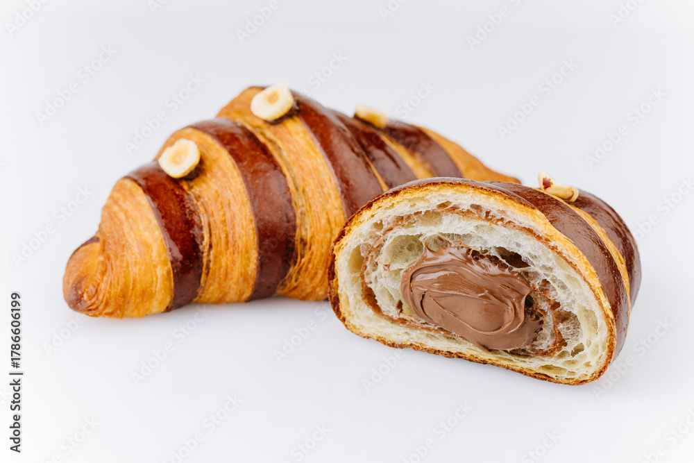 Fototapeta premium Chocolate hazelnut croissant with creamy filling and glossy crust on white background