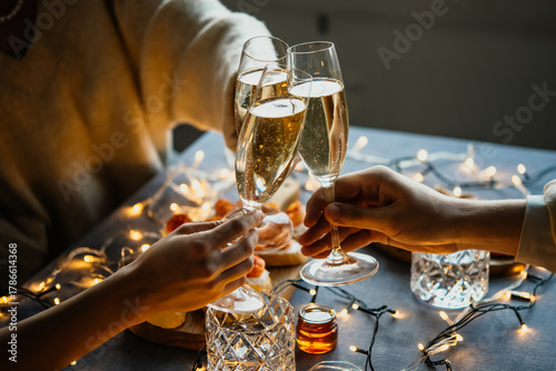 Friends celebrating Christmas or New Year eve party with champagne or sparkling wine.