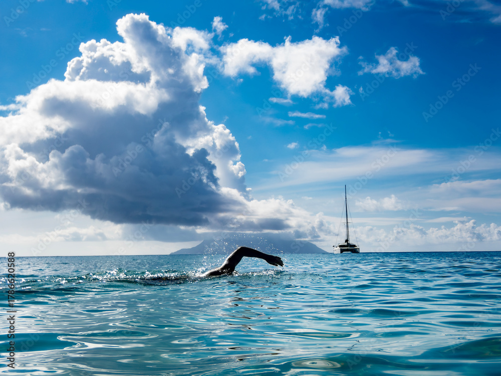 Fototapeta premium Open Water Swimming with Sailboat and Dramatic Cloudscape
