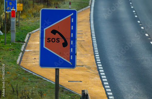 Controversial refuge on a SMART motorway where there is no hard shoulder. Yellow safety refuse with large SOS sign on an empty motorway with no cars.