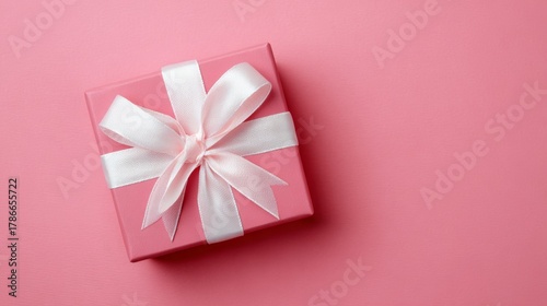 Gift box with a white ribbon on a pink background, perfect for celebrations and special occasions