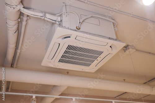 Interior air handling components view, Ceiling mounted air conditioning and ventilation setup, Commercial building HVAC infrastructure with technician inspection scene