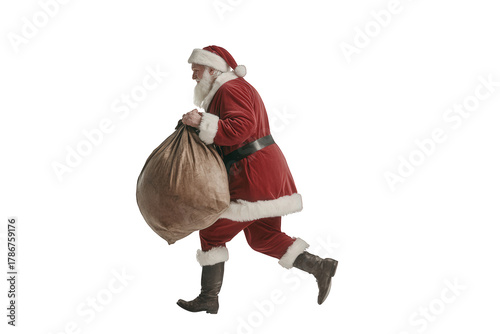 Santa claus isolated on transparent background, carrying a sack, dressed in a red suit, symbolizing christmas and holiday cheer, walking with a bag full of gifts