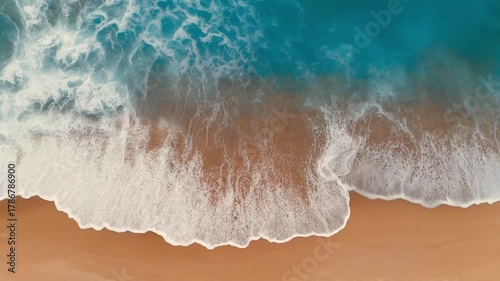 Aerial view of ocean waves washing over a sandy beach creating a textured and dynamic water and sand interaction